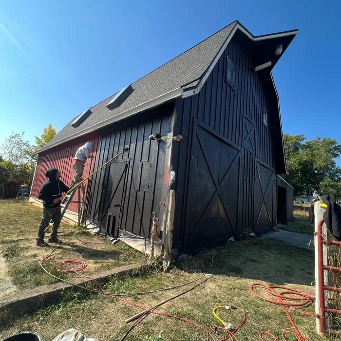 Crew spraying the gambrel barn elevation from red to black